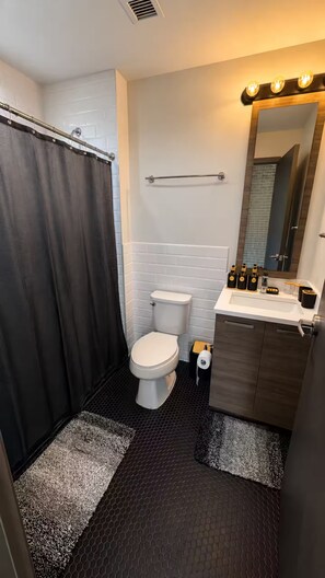 Ein Badezimmer mit Dusche, Toilette, Waschbecken und Spiegel.