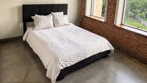 A bedroom with a bed, a window with a view, and a ceiling light fixture. - Downtown Dallas 2BR-2 Bath Loft (Dallas)