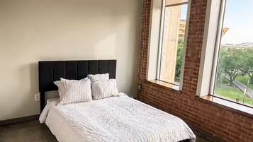 A bedroom with a bed, a window with a view, and a ceiling light fixture.