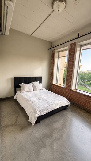 Ein Schlafzimmer mit einem Bett, einem Fenster mit Blick und einer Deckenleuchte.