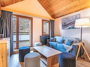 A modern living room with a wooden ceiling, a sofa, ottomans, a coffee table, and a floor lamp. - Les Hauts de Vaujany by Interhome (Vaujany)