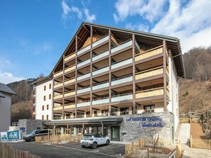 Ein mehrstöckiges Hotel mit einer Steinfassade, Holzbalkonen und einem Schild, das es als Ferienwohnung kennzeichnet.
