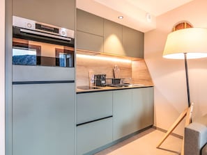 A modern kitchen with built-in appliances, a coffee machine, and a lamp. - Les Hauts de Vaujany by Interhome (Vaujany)