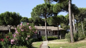 Ein Gebäude mit einem Ziegeldach, umgeben von Bäumen und einem Garten mit rosa Blumen.