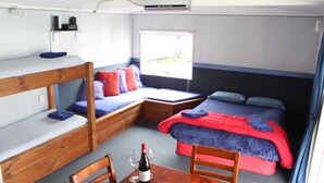A bunk bed room with a table, wine, and fruit.
