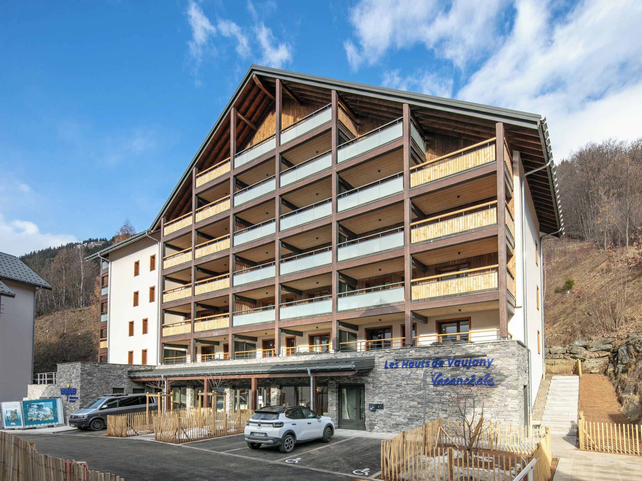 Un hotel de varios pisos con fachada de piedra, balcones de madera y un letrero que indica que es un alquiler vacacional.