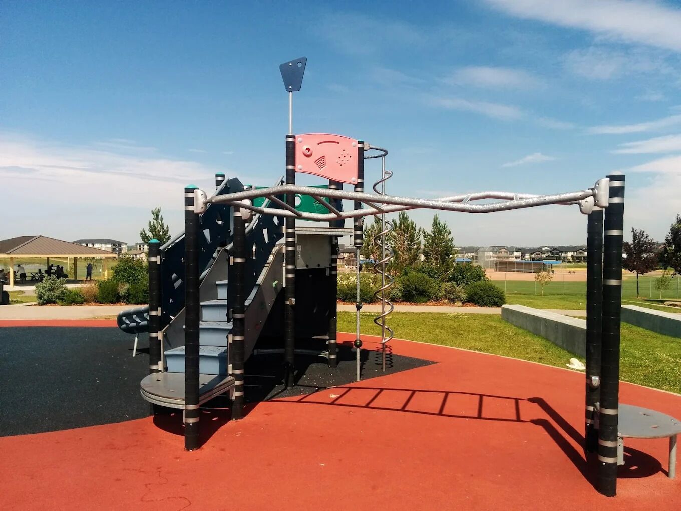Ein Spielplatz mit Klettergerüst, Rutsche und Schaukeln.