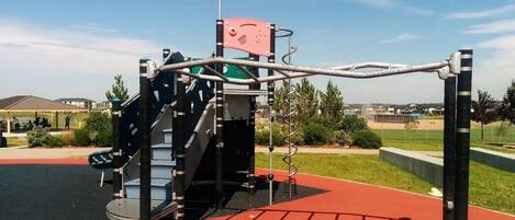 Ein Spielplatz mit Klettergerüst, Rutsche und Schaukeln.