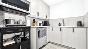 Una cucina moderna con elettrodomestici in acciaio inossidabile, mobili bianchi e un piano di lavoro nero.