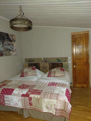 A bedroom with a bed, a wooden door, and a ceiling light fixture. - La Halte de Dakota, a unique bed-and-breakfast nestled in the heart of nature. (Chamouillac)