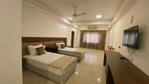 A hotel room with two beds, a TV, a desk, and a ceiling fan.
