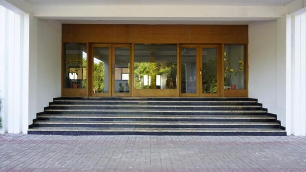 A building entrance with a set of stairs leading up to a wooden door with glass panels.