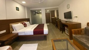 A hotel room with a bed, desk, chair, TV, and a ceiling fan.