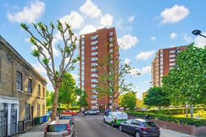 Calle con coches estacionados, un ciclista y edificios residenciales altos.