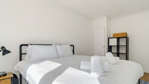 A neatly made bed with white linens, a black metal headboard, a bedside lamp, and a small wooden nightstand with a lamp. - New * Zone 1 - 2 bed slps 5 quiet modern 800mps Wifi a home from home! (London)