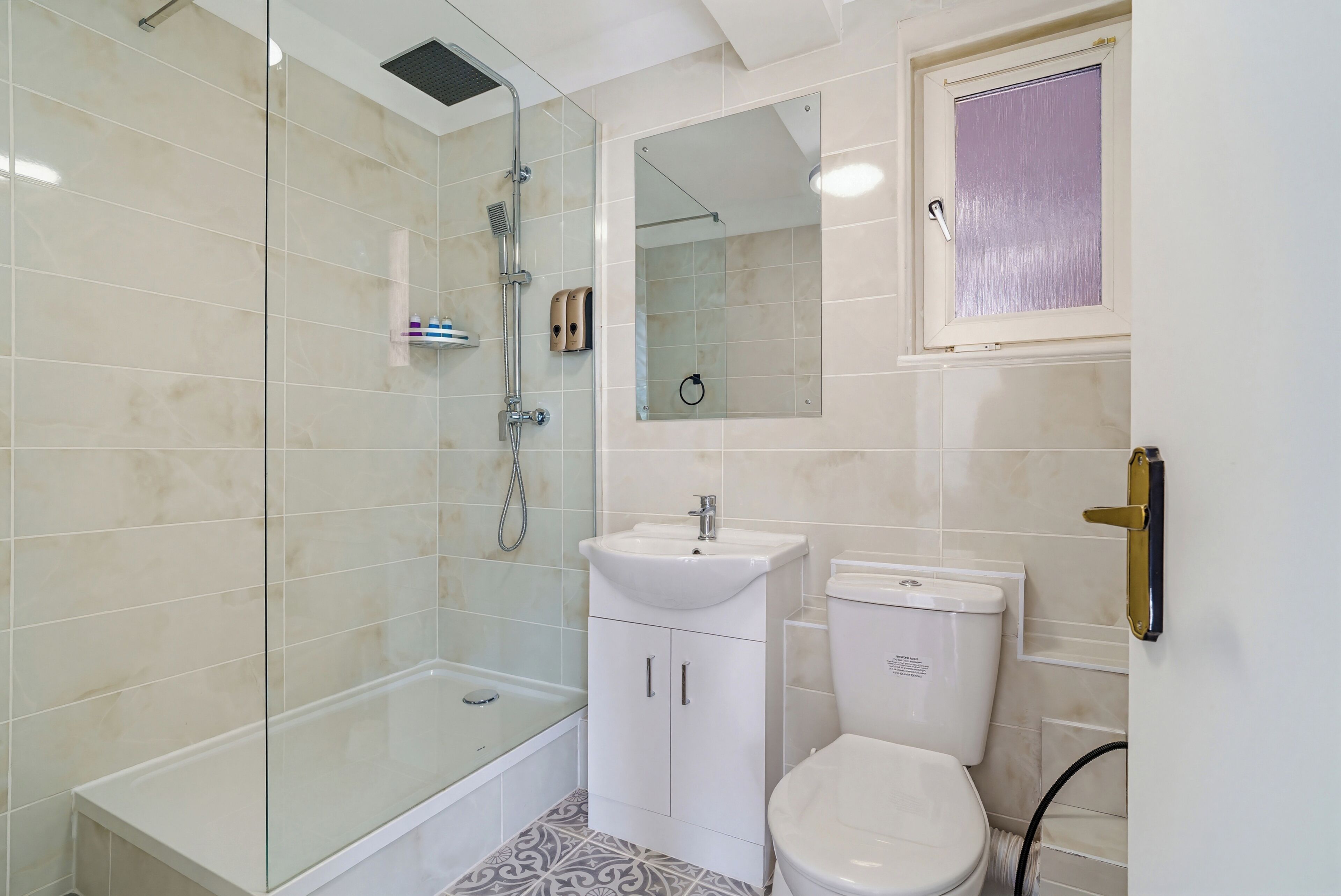 A modern bathroom with a glass-enclosed shower, a white sink, and a toilet.