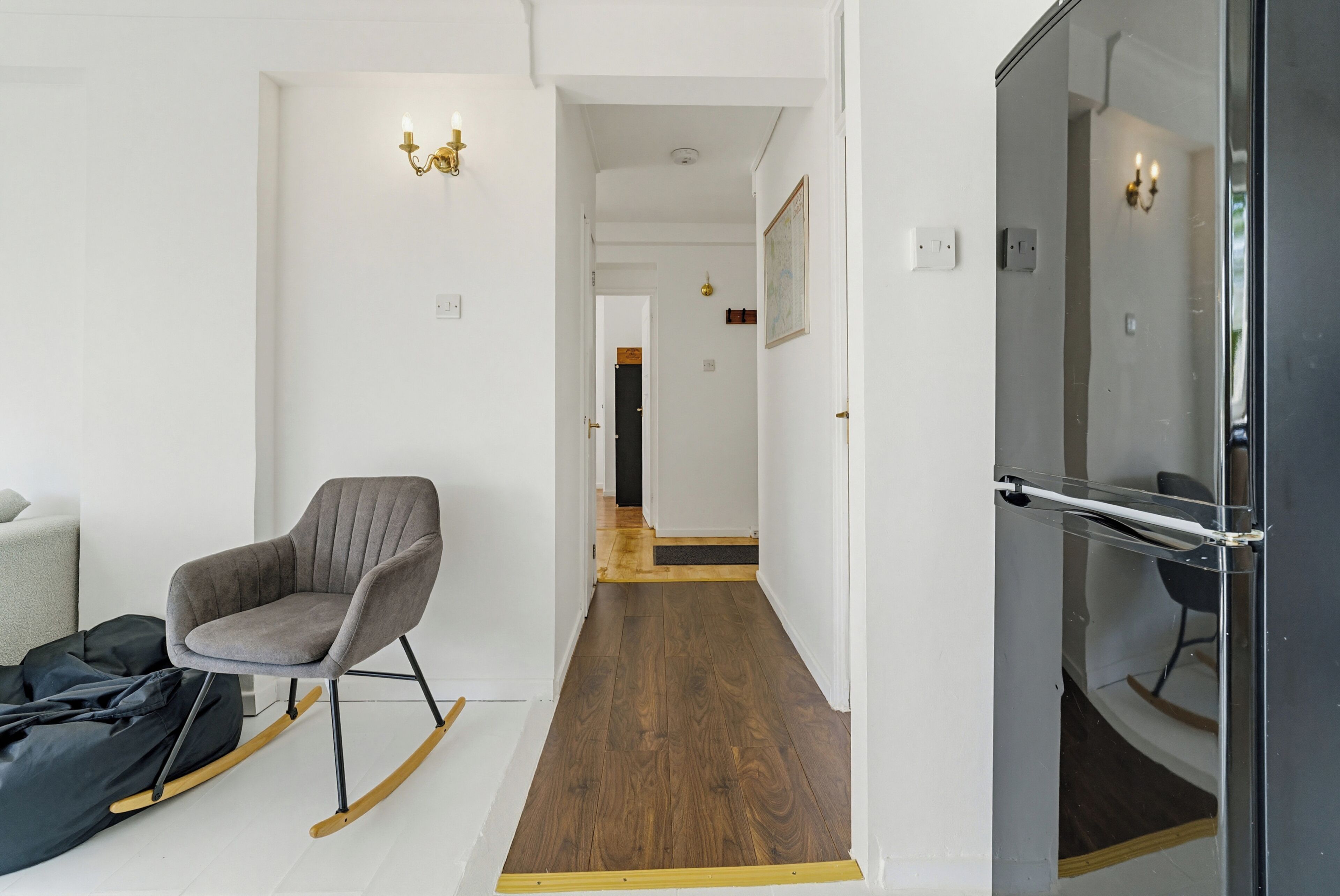 Um interior moderno com uma poltrona estofada cinza, um sofá preto e piso de madeira.