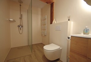 Un baño con ducha, inodoro y un armario de madera.