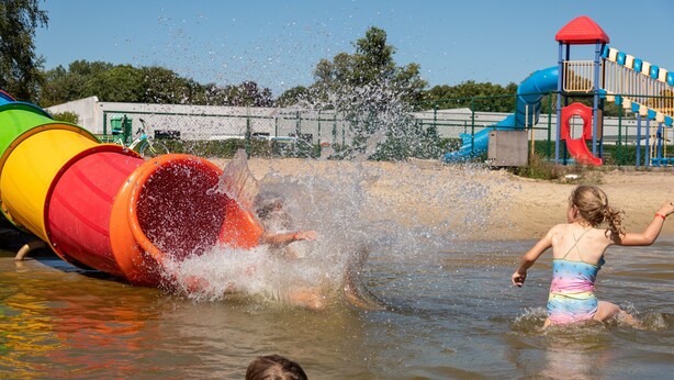 Ein Wasserspielbereich mit einer großen Rutsche und einer Spielanlage im Hintergrund.