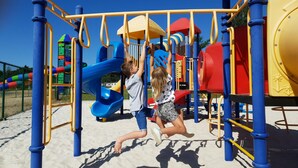 Kinder spielen auf einem Spielplatz mit verschiedenen Spielgeräten.