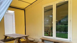 Ein Zimmer mit einer hölzernen Sitzbank, einem Tisch und einem Fenster mit Blick auf Grünflächen.