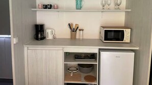 Eine kleine Küche mit Mikrowelle, Kaffeemaschine und Kochgeschirr auf der Arbeitsfläche.