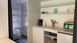 Una cocina compacta con cafetera, utensilios y un refrigerador pequeño.