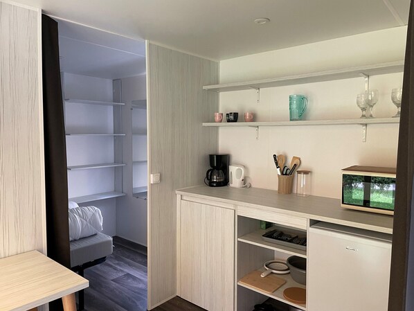 Una cocina compacta con cafetera, utensilios y un refrigerador pequeño.