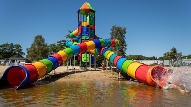 Un área de juegos con agua que incluye un tobogán y una torre de agua.