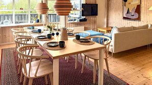 A dining area with a wooden table set for four, surrounded by white chairs. - Large holiday home close to the beach (Ebeltoft)