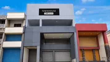 Un immeuble à plusieurs étages portant une enseigne indiquant « TOWNHOUSE » et « OYO-Serviced », ce qui signifie qu’il propose des logements avec services.