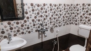 Un baño con lavamanos, inodoro y ducha. Las paredes tienen un estampado de lunares.