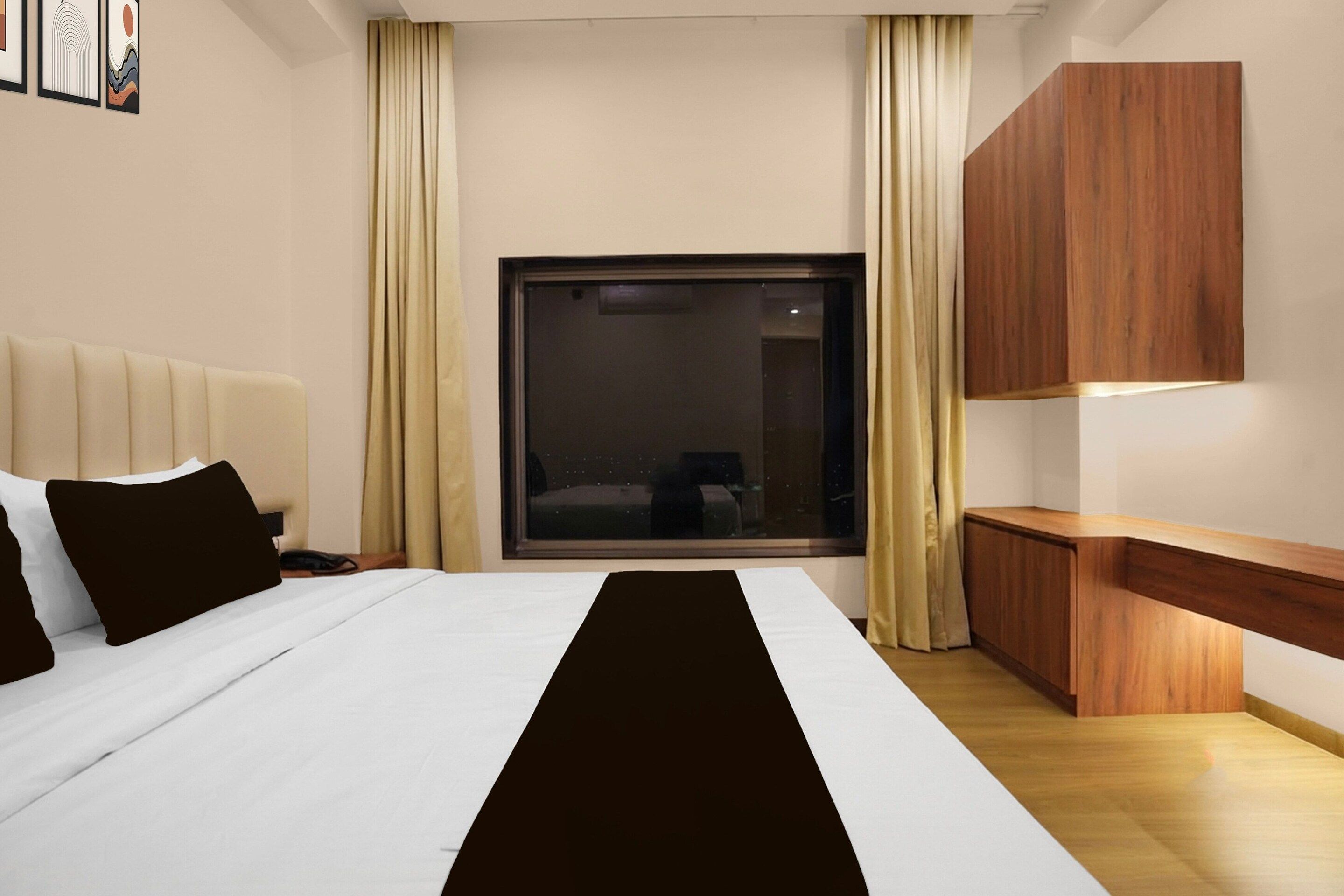 A modern hotel room with a large bed, a wooden desk, and a sliding door to the outside.