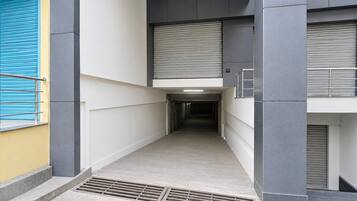 Un couloir aux volets fermés, avec une rambarde en métal et un sol carrelé.