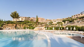Ein Resort mit großem Pool, mehreren Gebäuden und einer Hügelside mit Bäumen und Sträuchern.