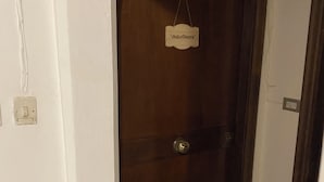 A closed wooden door with a sign above it, a white wall, and a green mat at the door's base. - Charming 2-bedroom apartment with AC in Vibo Valentia (Vibo Valentia)