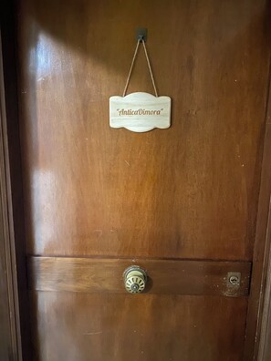 Une porte en bois avec une poignée en métal et une enseigne au-dessus.