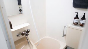 Een badkamer met een wastafel, spiegel en twee flessen shampoo en douchegel op de tank van het toilet.