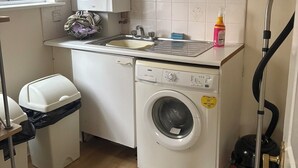 Una cocina compacta con lavadora, un lavabo, una ventana y un aspirador.