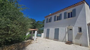 Un edificio su due piani con facciata bianca, diverse finestre con persiane e un vialetto ghiaioso.