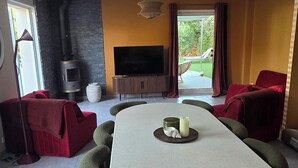 Un soggiorno moderno con un grande tavolo da pranzo, posti a sedere confortevoli, un caminetto e una televisione.