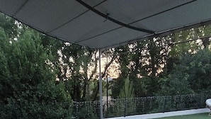 Patio esterno con piscina, dotato di divanetto, tavolino rotondo e poltrona a dondolo.