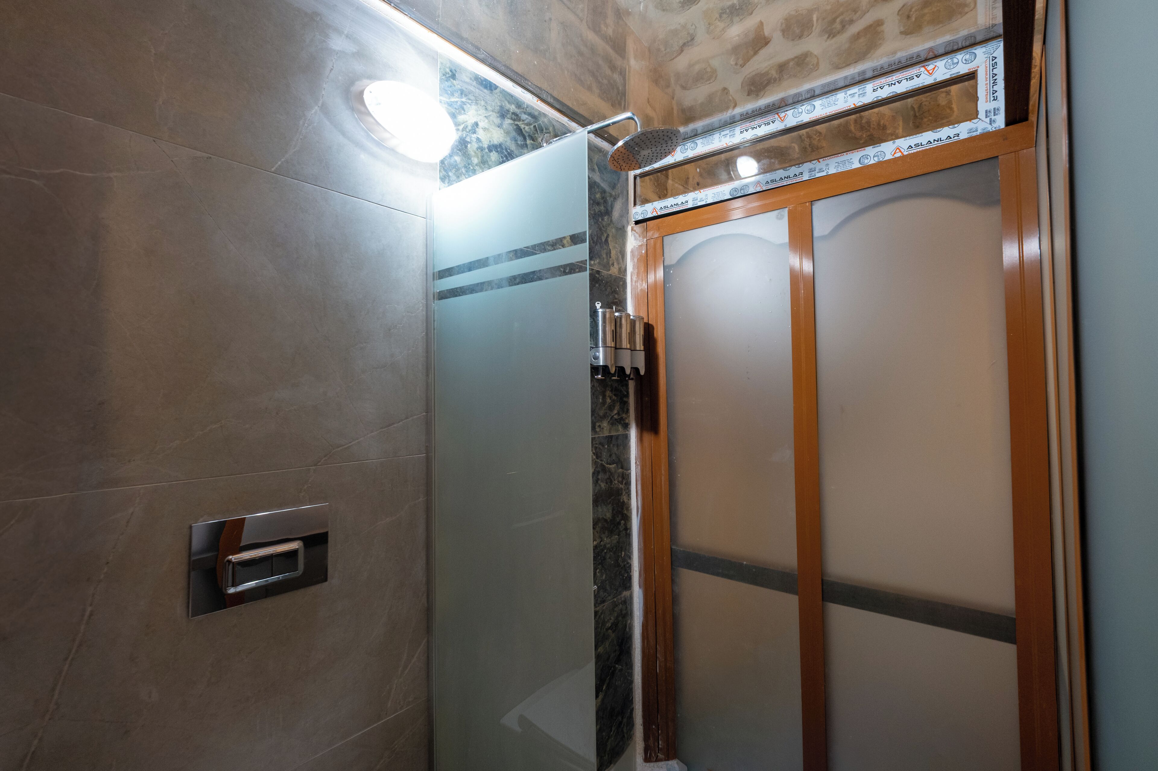 Una ducha con puerta de vidrio, marco de madera y pared de azulejos.