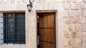 Un edificio de piedra con puerta de madera y ventana con barrotes.