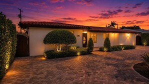 Een huis met een verharde oprit, een verzorgd gazon en een zonsondergang.