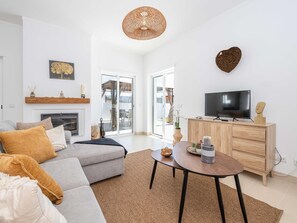Ein modernes Wohnzimmer mit Sofa, Fernseher, Holzschrank und Kamin.