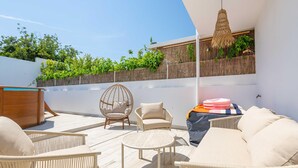 A rooftop patio with wicker furniture, a hanging light fixture, and a view of greenery. - Casa Aurea V3 com Piscina Privada (Tavira)