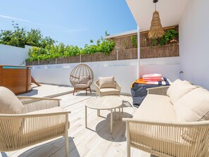 Eine Dachterrasse mit Korbmöbeln, einer Hängelampe und Blick auf Grünflächen.