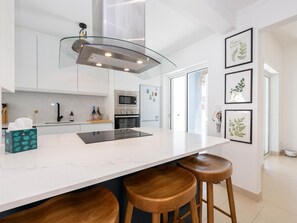 Eine moderne Küche mit einer zentralen Kochinsel, Edelstahlgeräten und Holzbarhocker.