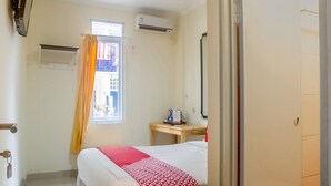 A hotel room with a bed, a desk, a window with curtains, an air conditioning unit, and a door. - Luxury Deluxe DBL Retreat W/ Free Wifi and Parking (Jakarta)